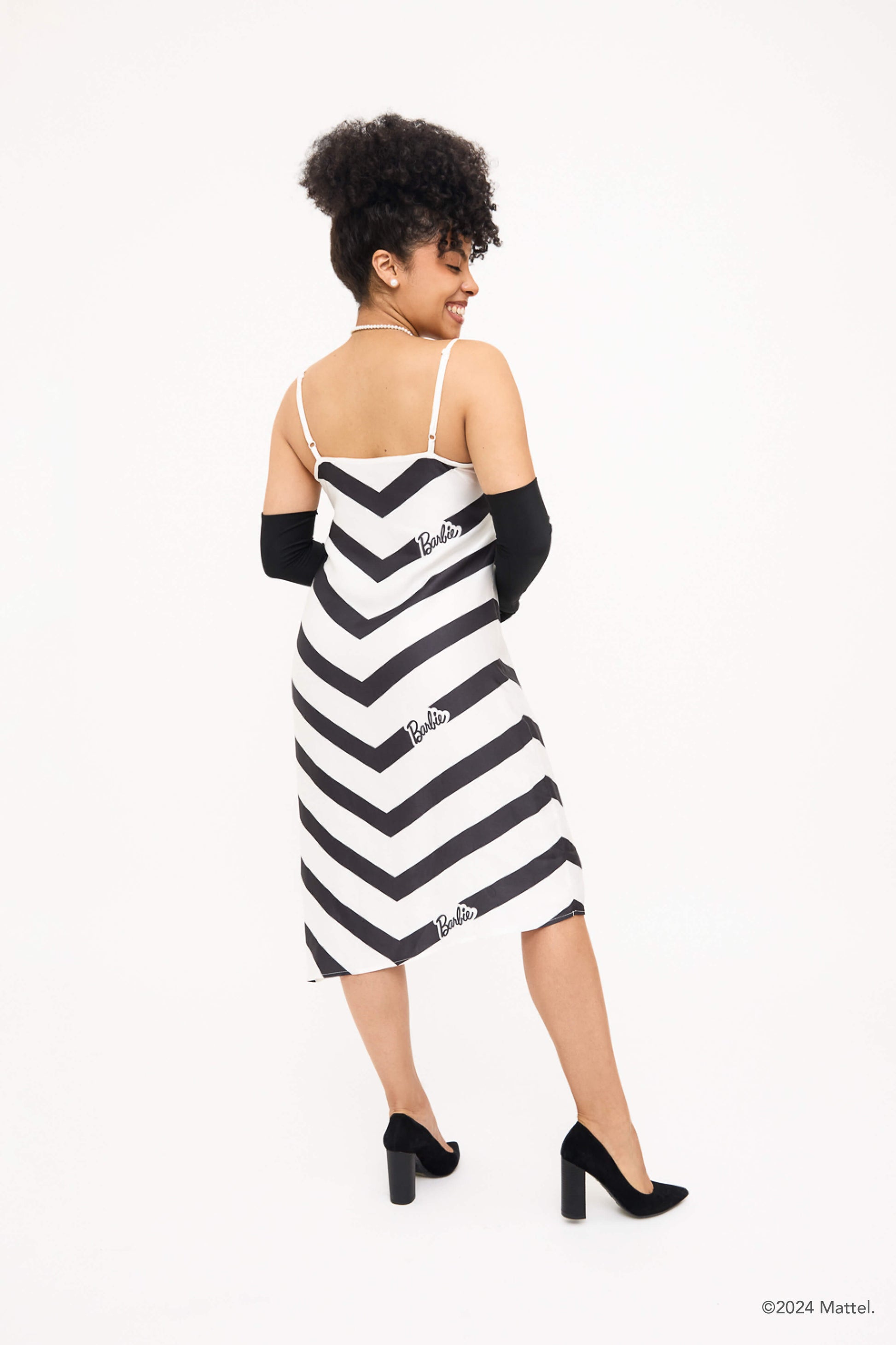 Back view of model wearing black and white chevron dress styled with long black gloves and black heels.