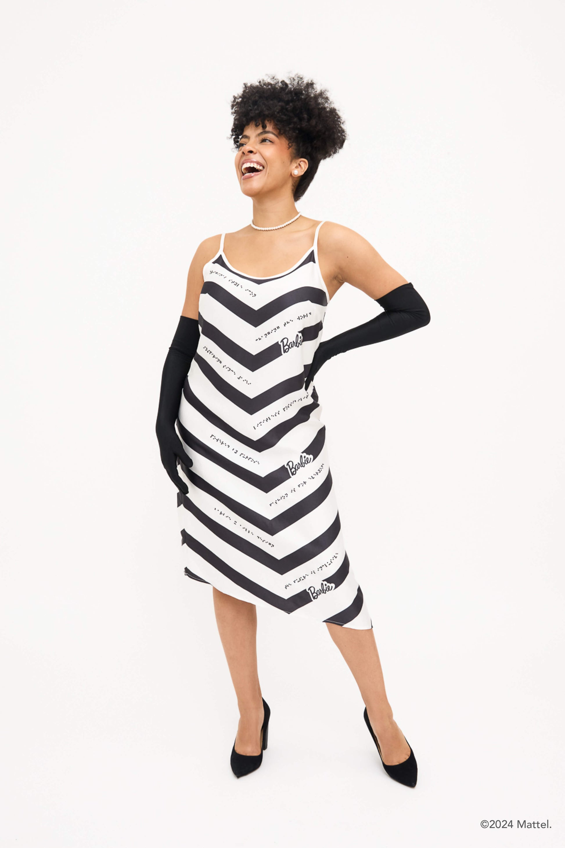 Front view of model wearing black and white chevron dress styled with long black gloves and black heels.