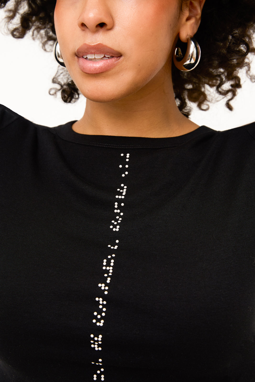Close up of braille beadwork detailing placed vertically on center front of shirt. White braille reads "making inclusion an expectation not an exception."