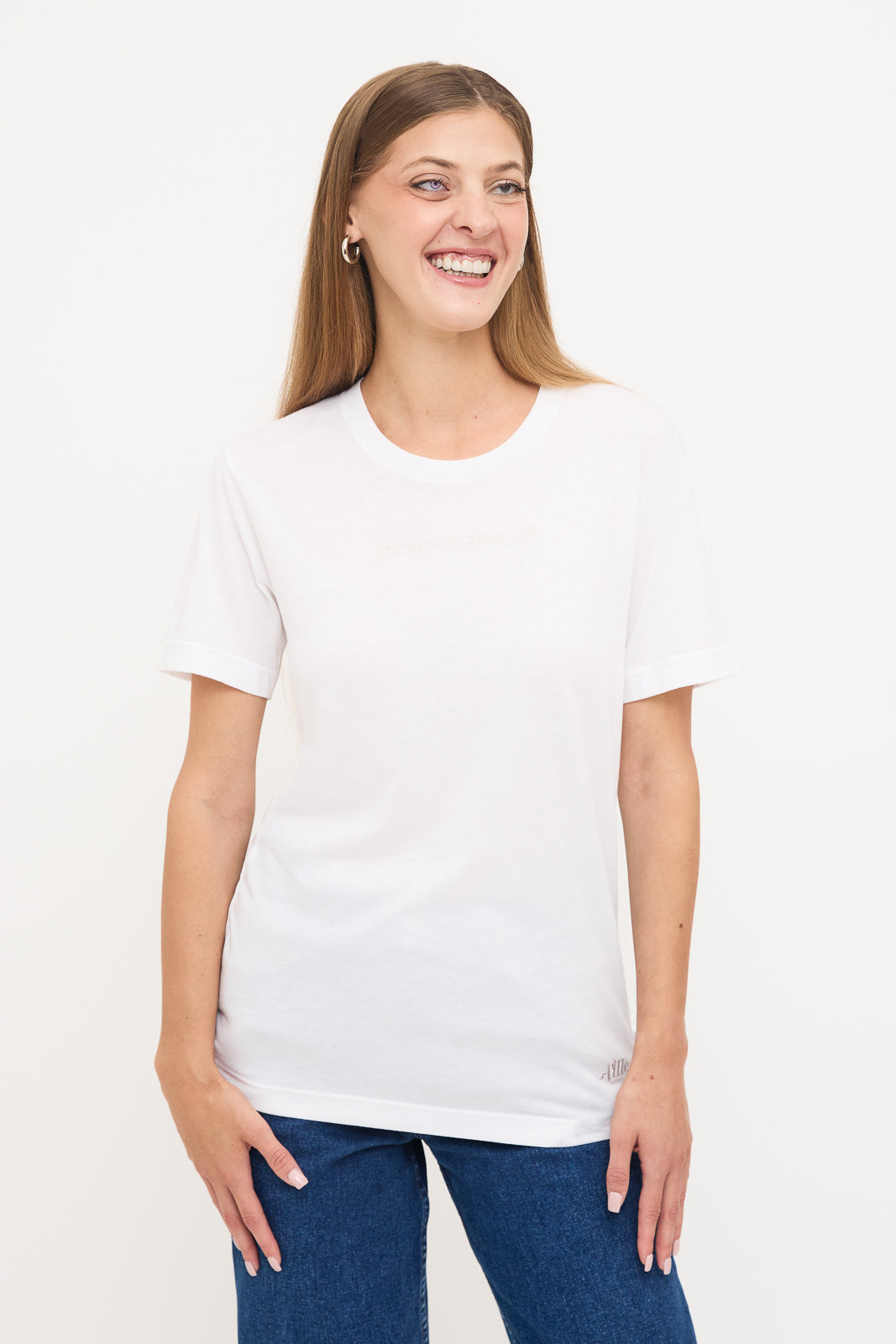 Front View of Woman's White T-Shirt: Young blind woman smiling, wearing a white t-shirt with white braille beadwork below the neckline.