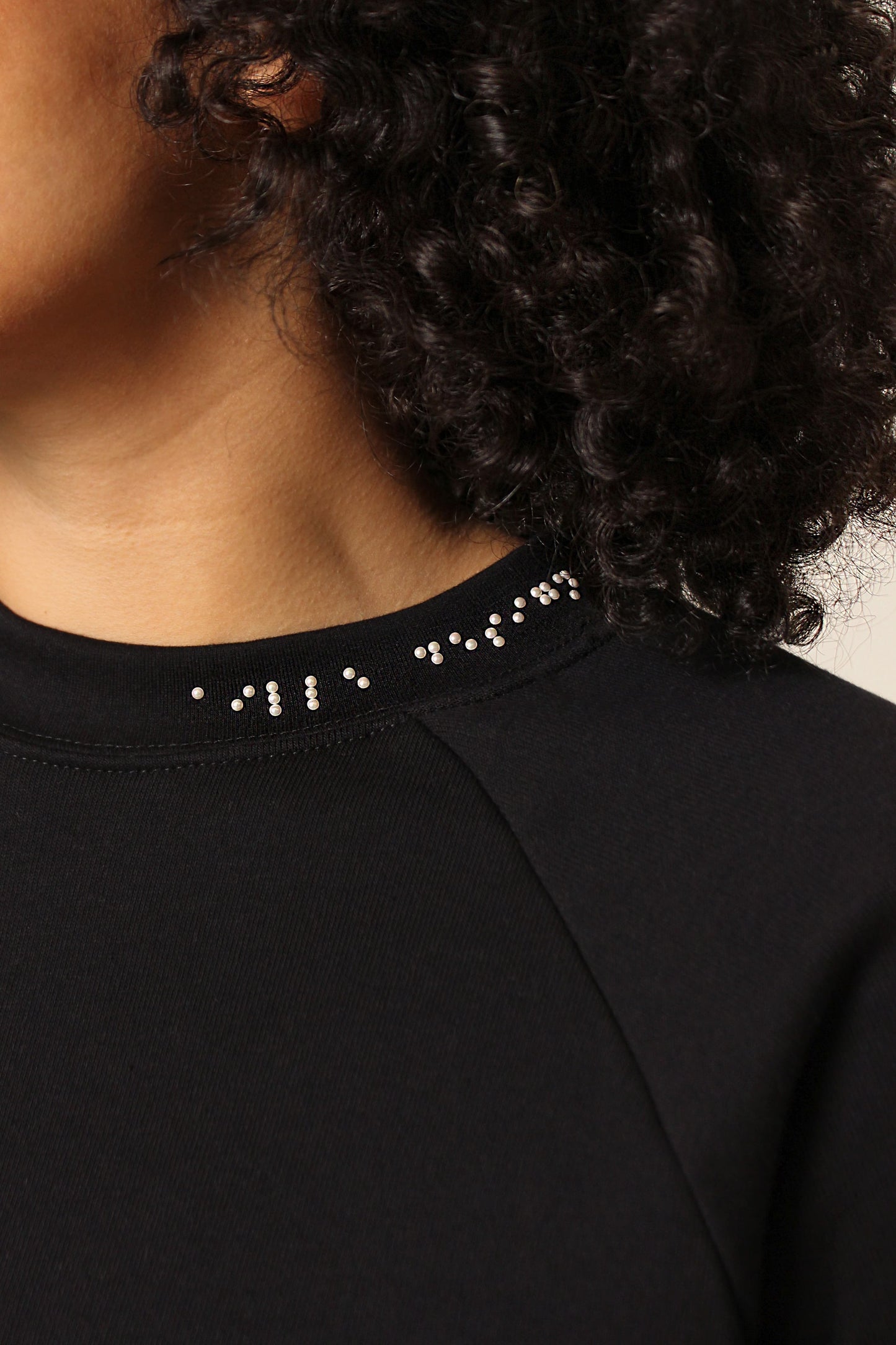 Close up of braille beadwork detailing placed asymmetrically on the collar. White braille reads "aille design"