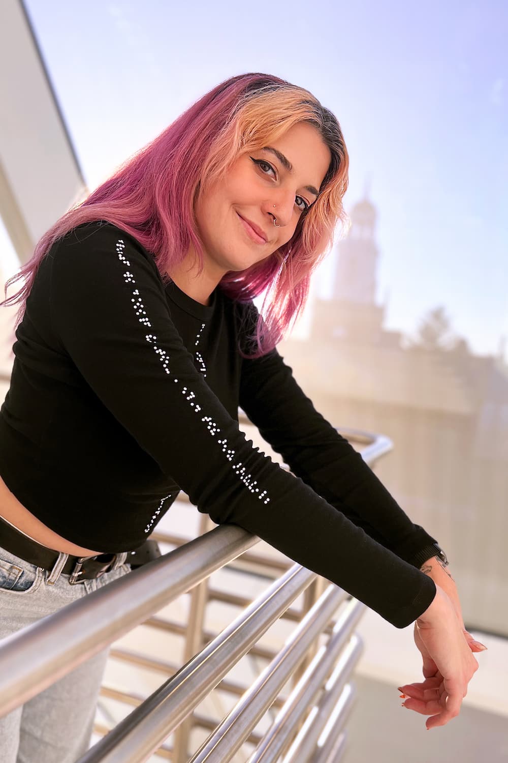 Model leaning over banister showcasing braille on shirt sleeves