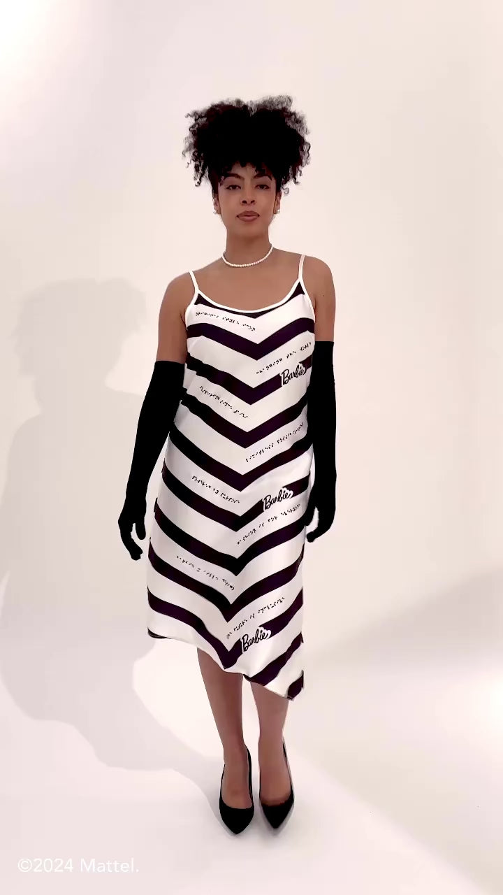 Model wears black and white chevron dress and moves around on set to showcase product details.