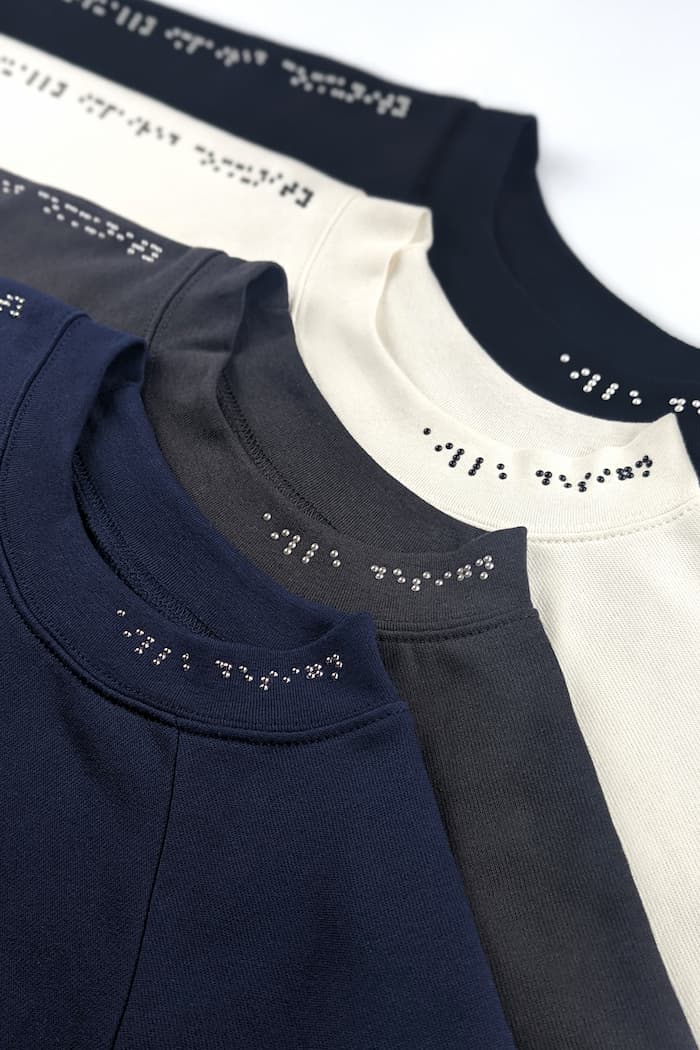 Braille sweater designs with asymmetrical braille placement. Braille is along one sleeve and half of neck area.