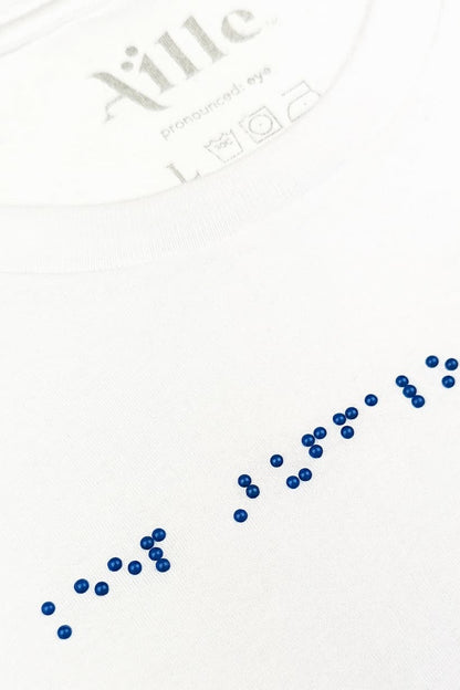 Close up of blue braille beadwork on white t-shirt.