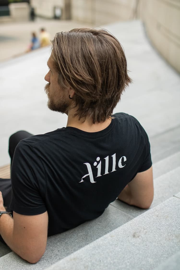 Back of man's black t-shirt has Aille Design logo 