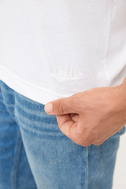 Logo Detail on White T-Shirt: Close-up of the bottom corner of a black t-shirt showing the "Aille" logo in white embroidery.