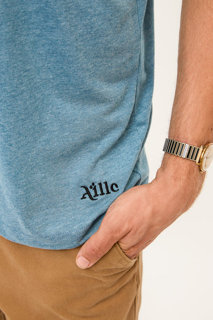 Logo Detail on Blue Grey T-Shirt: Close-up of the bottom corner of a blue grey t-shirt showing the "Aille" logo in black embroidery.