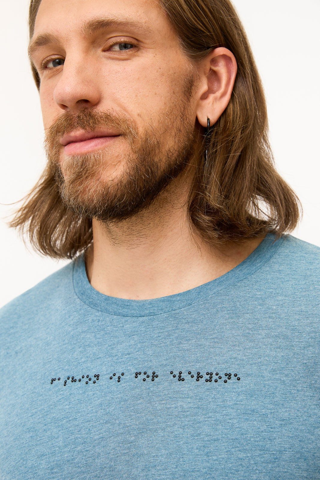 Braille Detail on Blue Grey T-Shirt: Close-up of black braille beadwork on shirt reads "fashion is for everyone."