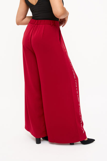 Back view of red wide-leg pants showcasing elastic waistband, belt loops, and side pockets.