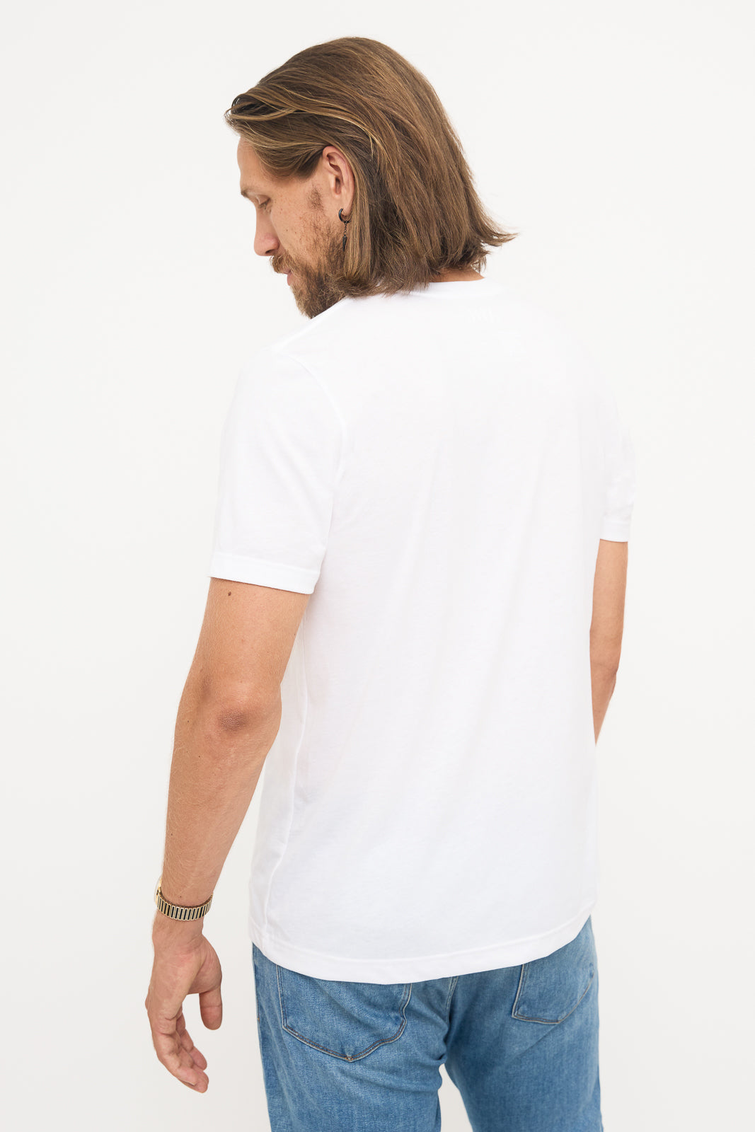 Back View of White T-Shirt: Young man with shoulder-length hair looking down, showing the back of a white t-shirt.