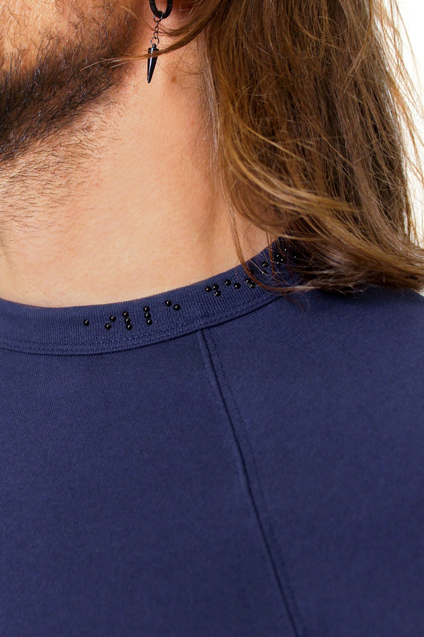 Close up of braille beadwork detailing placed asymmetrically on the collar. Black braille reads "aille design"