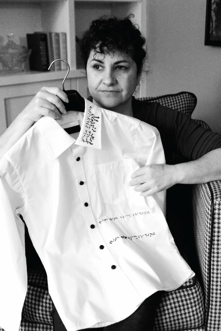 Black and white photo of visually impaired woman holding the first braille clothing prototype