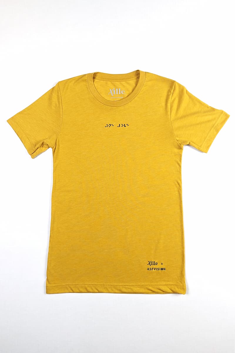 Flat lay photo of yellow t-shirt with black braille