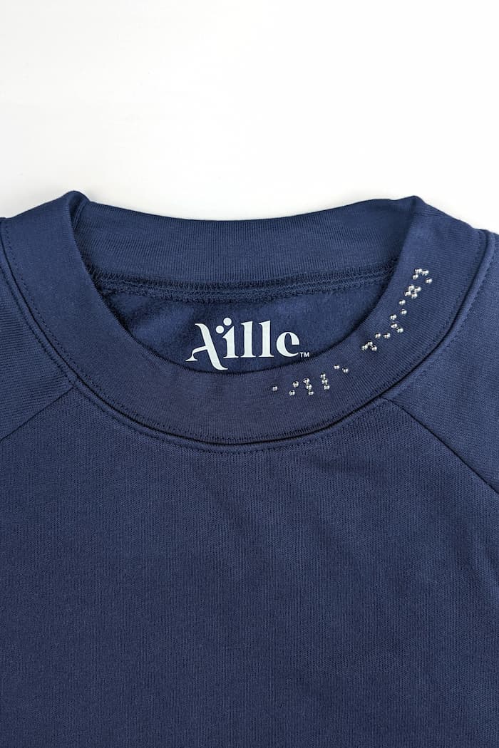 Chrome braille on neck on navy blue sweater