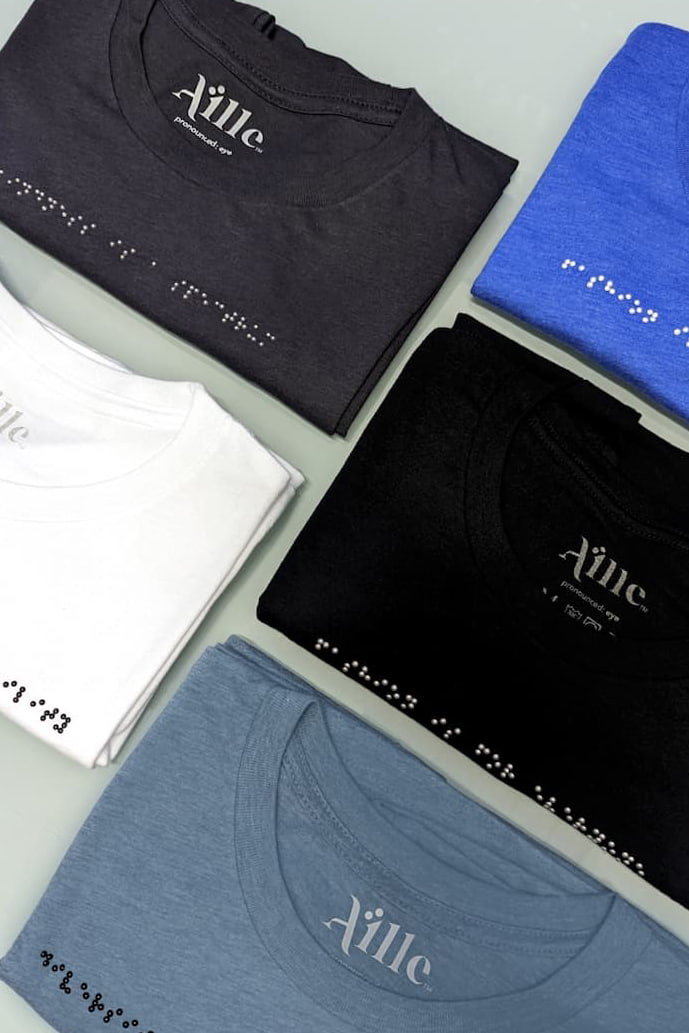 Braille clothing t-shirts in white, dark grey, black, royal blue, and light blue/grey