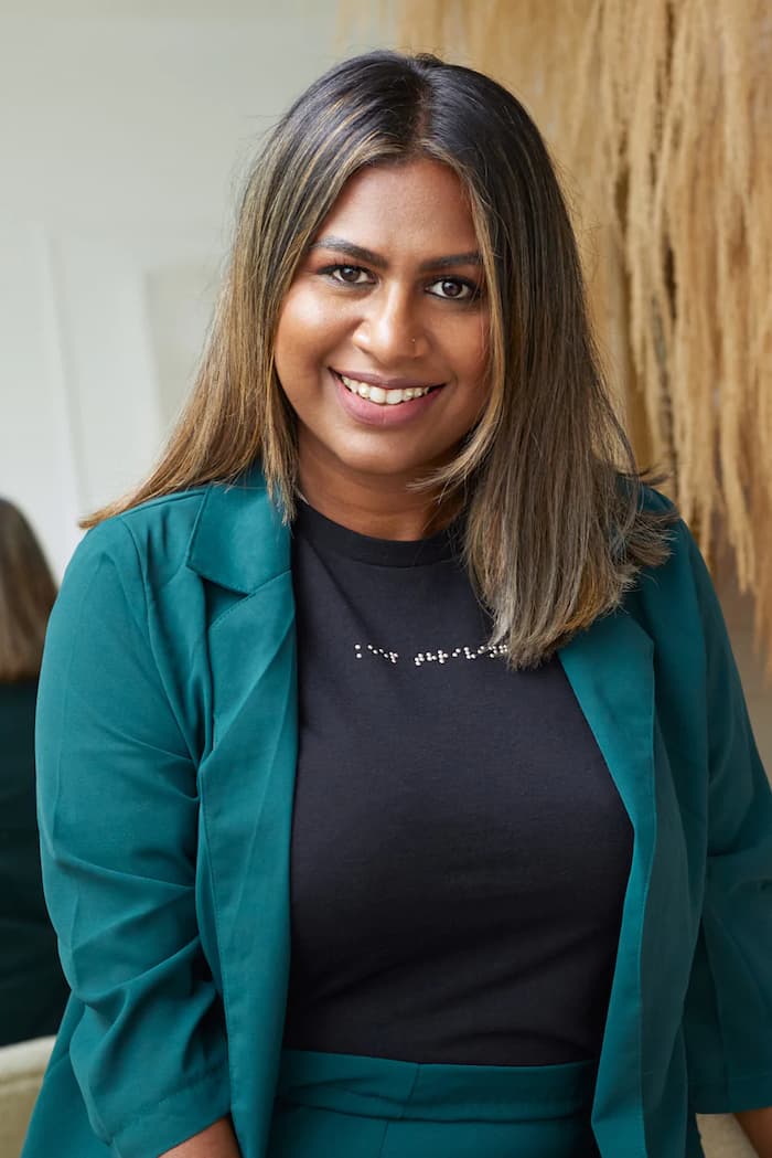 Visually impaired woman wearing black braille t-shirt with dark green pant suit