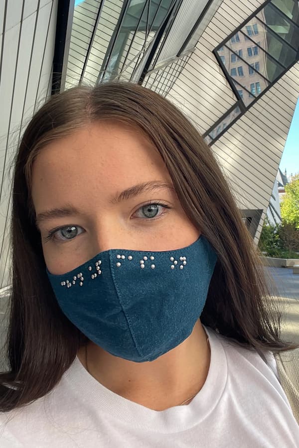 Young white woman wearing blue braille mask at the Royal Ontario Museum