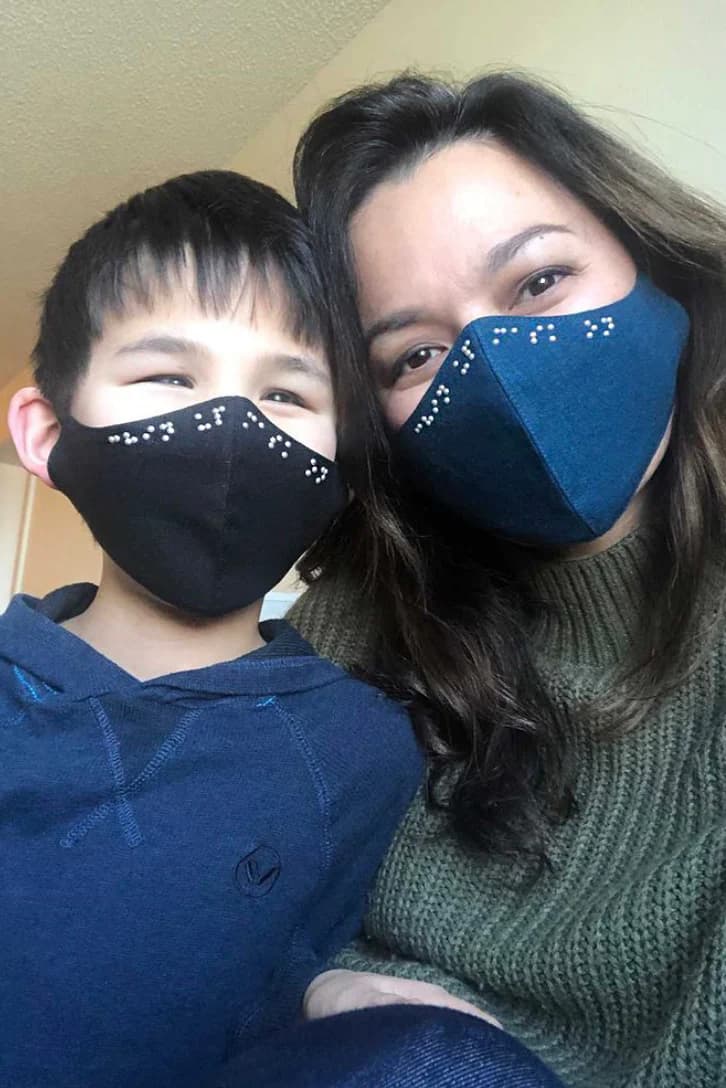 Visually impaired asian child and his mom wearing black and blue braille masks