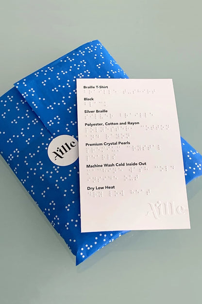 Accessible packaging with braille and large print information. Wrapped in blue tissue paper with simulated braille.