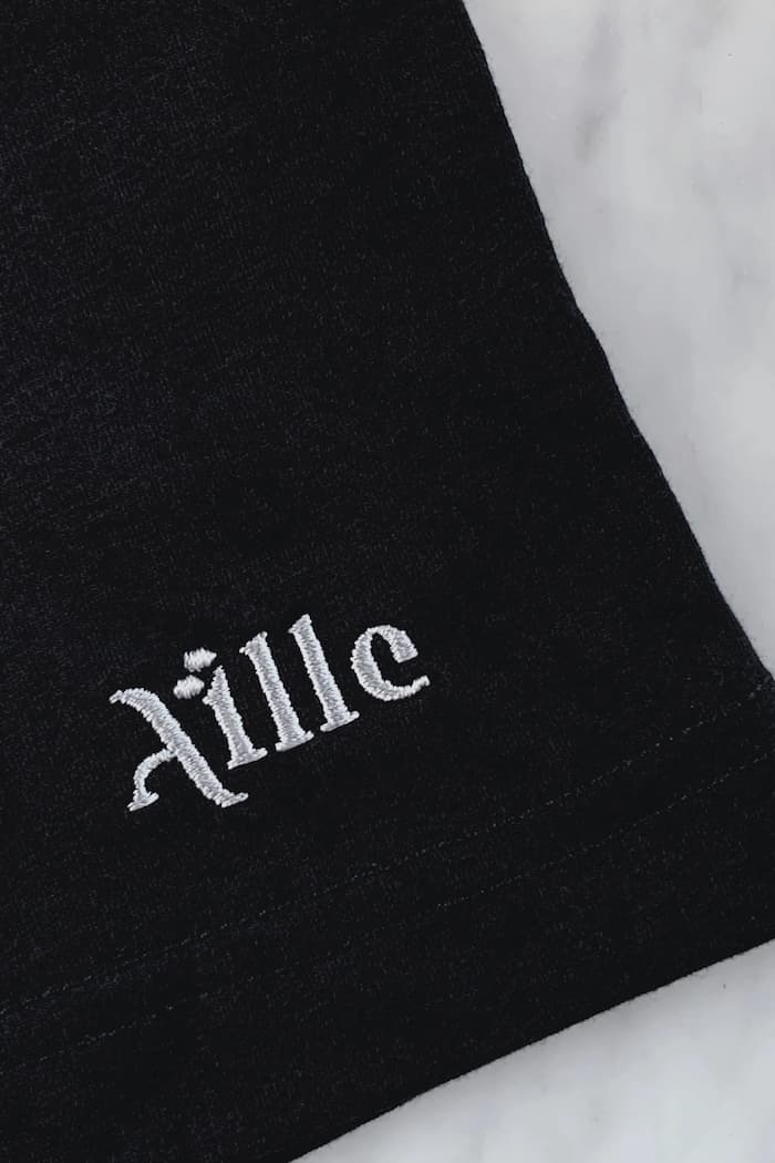 Close up of silver embroidered logo on black t-shirt