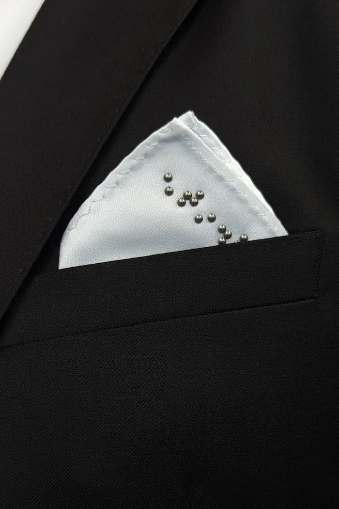 Close up of white folded pocket square in black suit.
