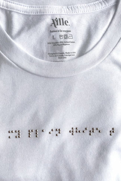 Close up of silver braille beadwork on white t-shirt