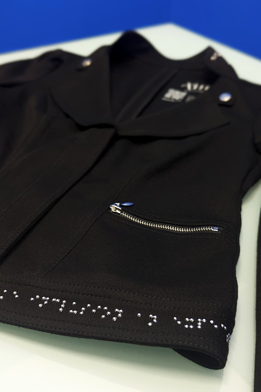 Detail photo of braille on hem/waistband of motto jacket