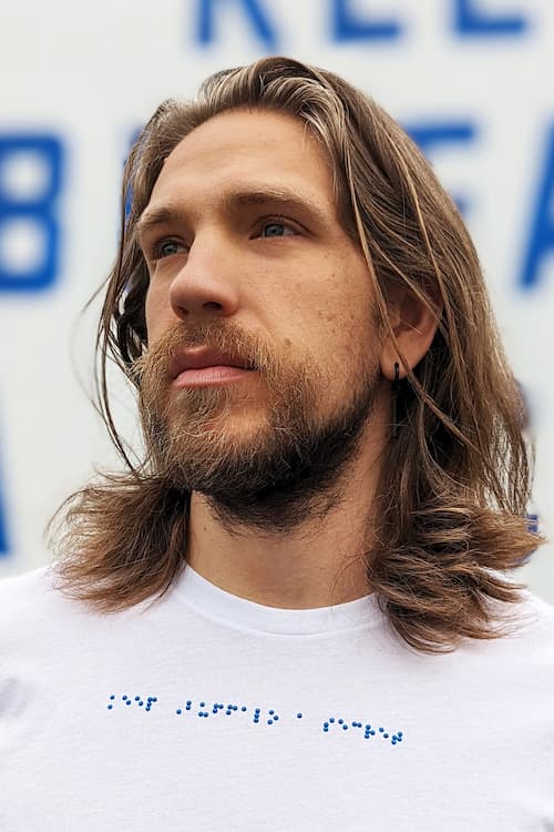 Close up of Jake wearing white t-shirt with blue braille