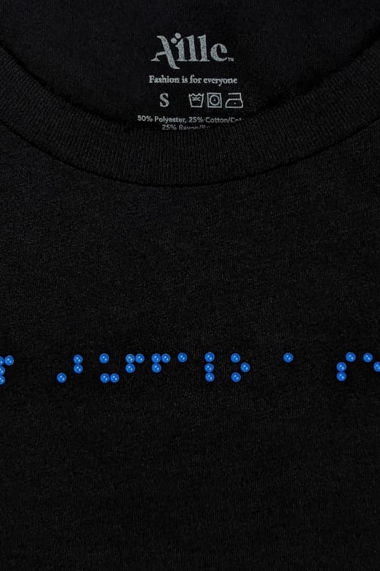 Close up of blue braille beadwork on black t-shirt.