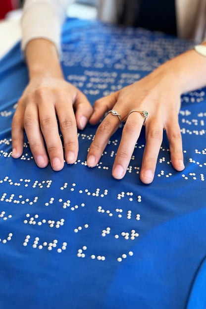 Close up of hands reading braille on blue braille dress